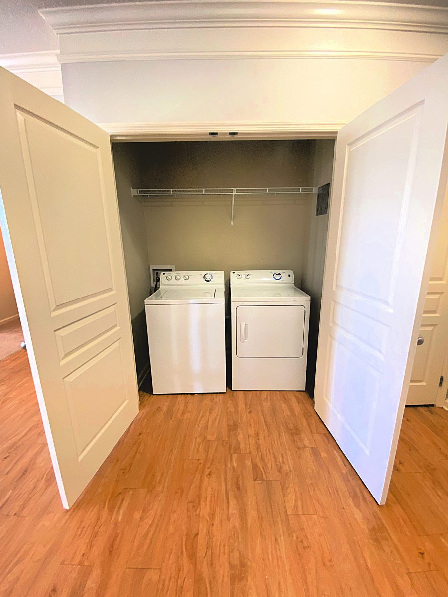 Open double door closet with washer and dryer and a single shelf