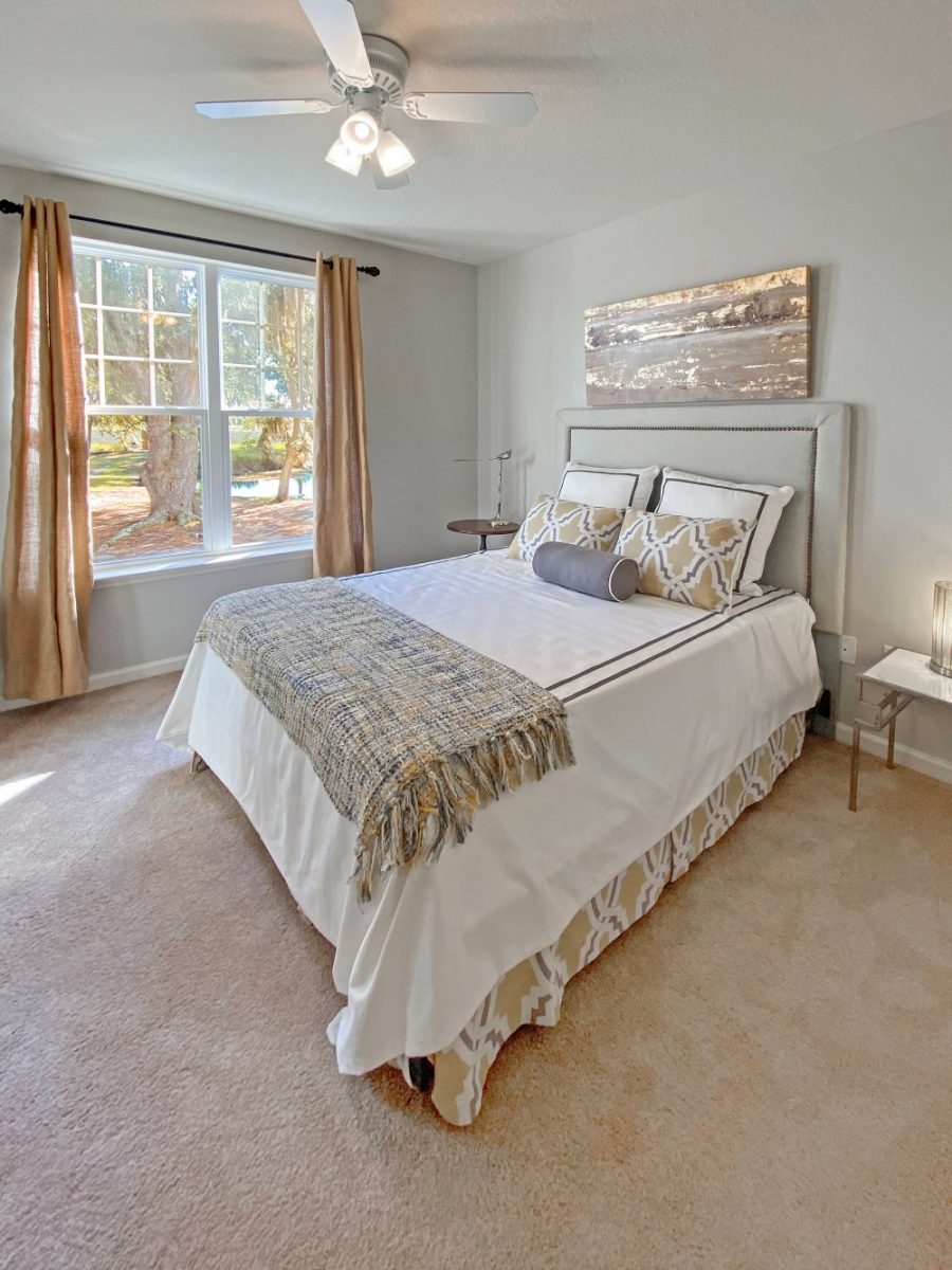 Carpeted bedroom with a queen bed, two night stands, and a large open window with a view of the beautiful marsh.