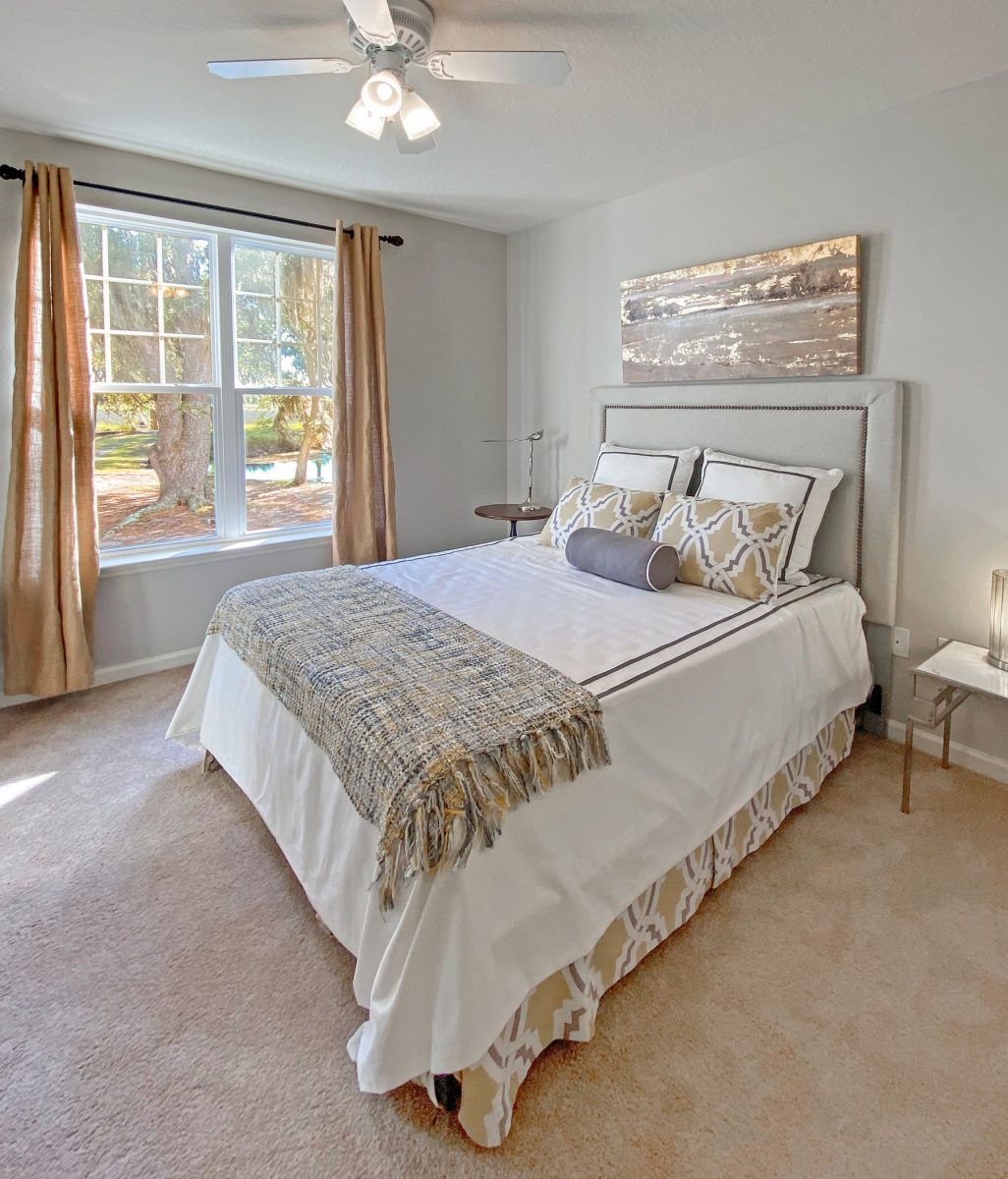 Carpeted bedroom with a queen bed, two night stands, and a large open window with a view of the beautiful marsh.